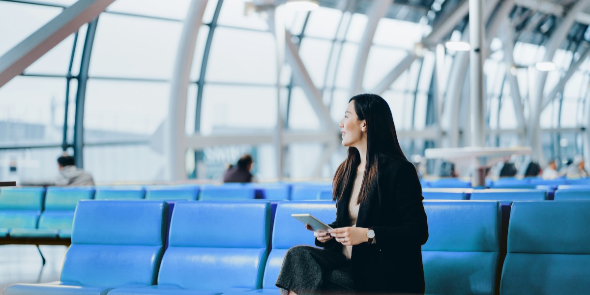 Woman sitting at the airport with a tablet in hand