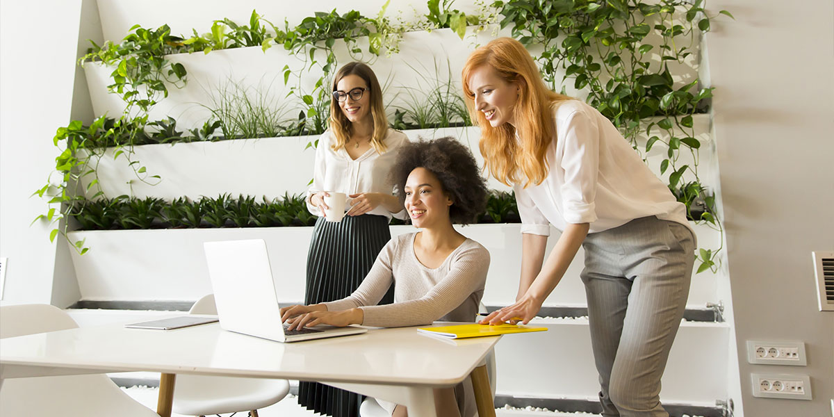 3 professional women huddle over computer