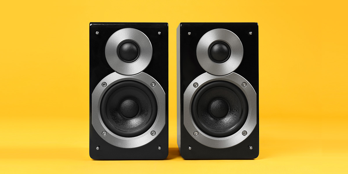 Two large speakers on yellow background. 