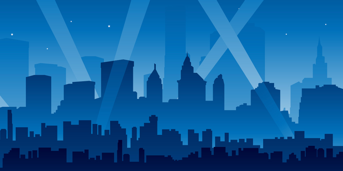 Silhouette of the New York City skyline with spot lights pointing in the sky.