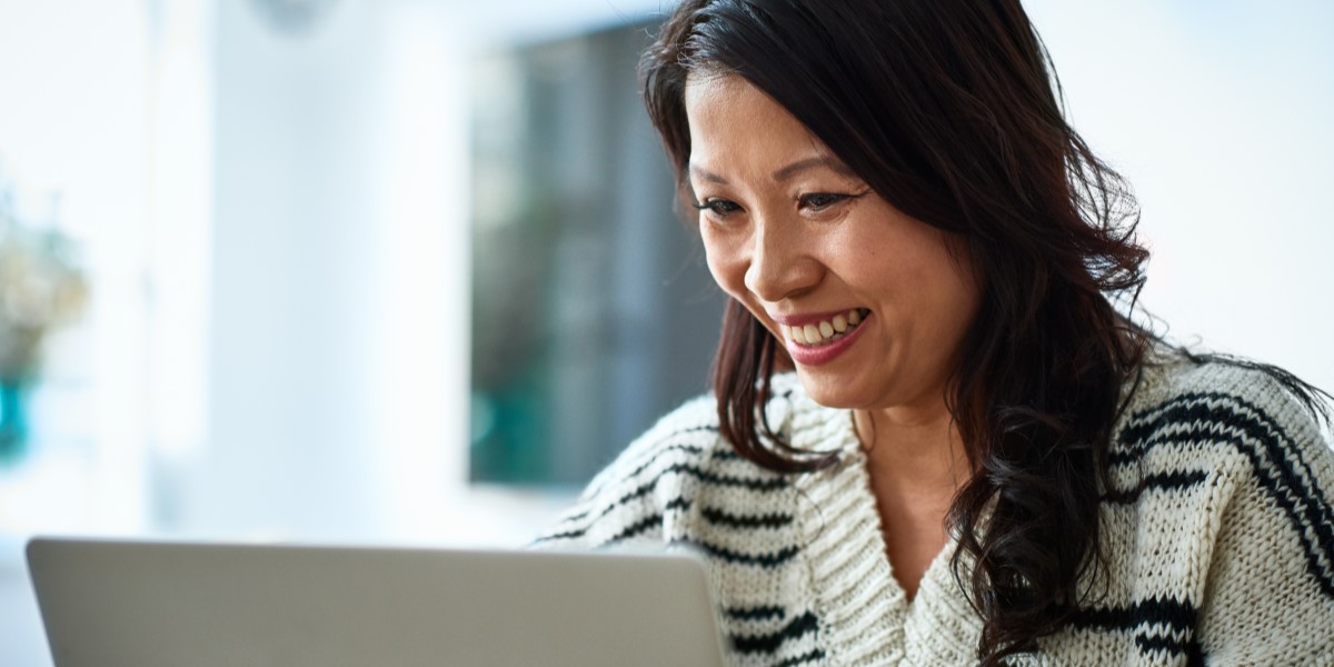 A woman smiling in front of a laptop screen