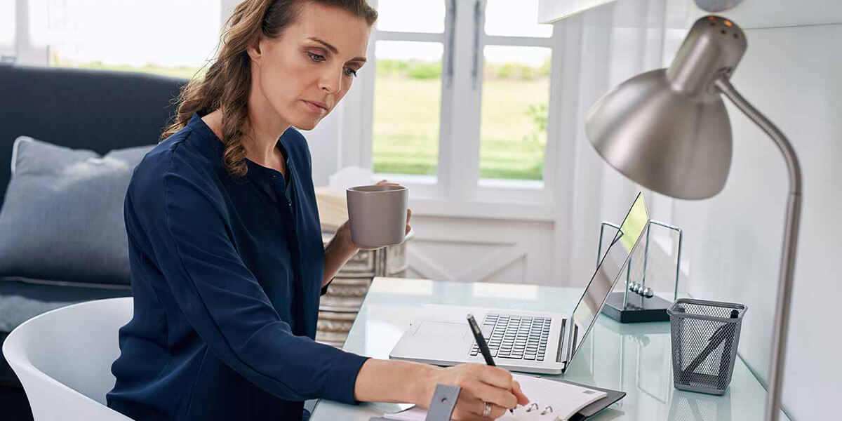 Woman sits at her desk and reviews her financial accounts after a data breach.