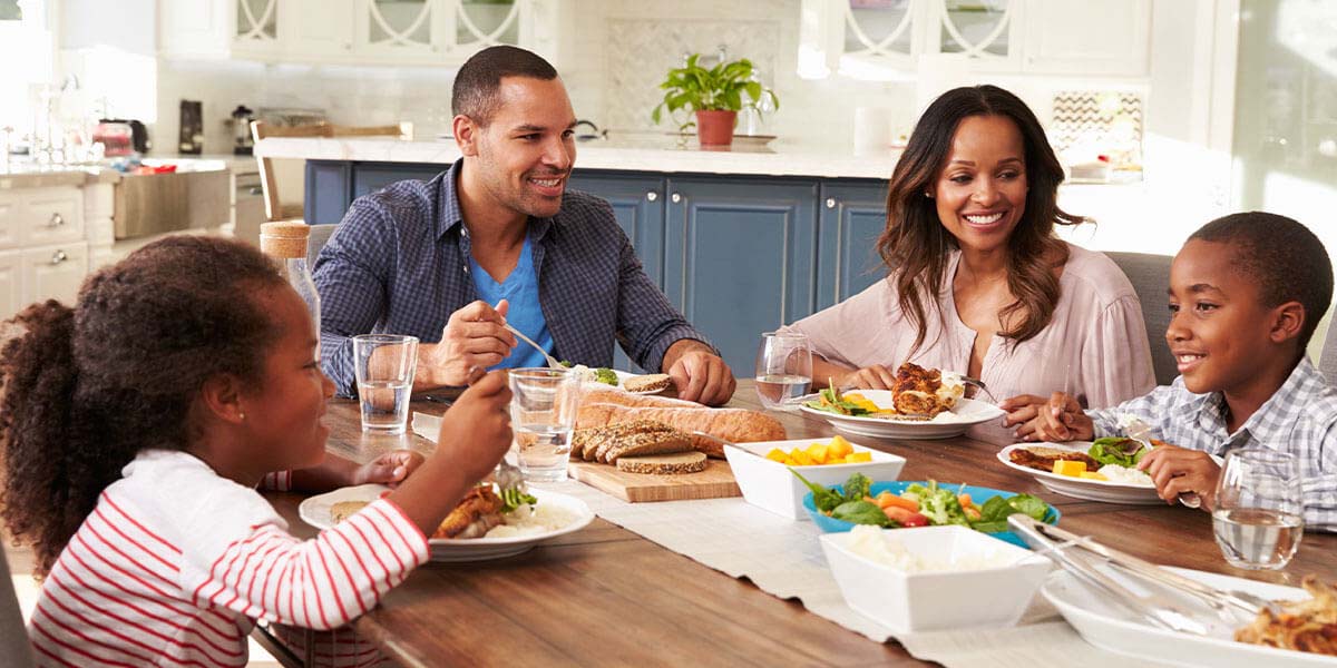 Couple sitting at the table in their home with their two, young children eating dinner