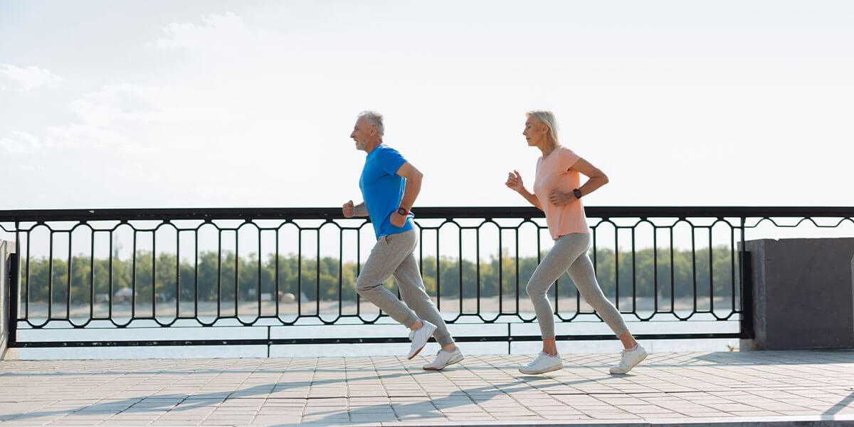 Older couple on a jog alongside the water.