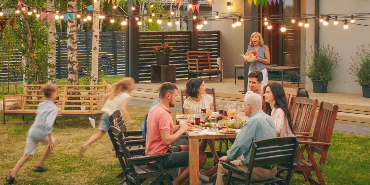 Family enjoying dinner outside in their shared family vacation home. 