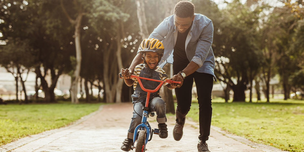 A father teaches his son how to ride a bike.