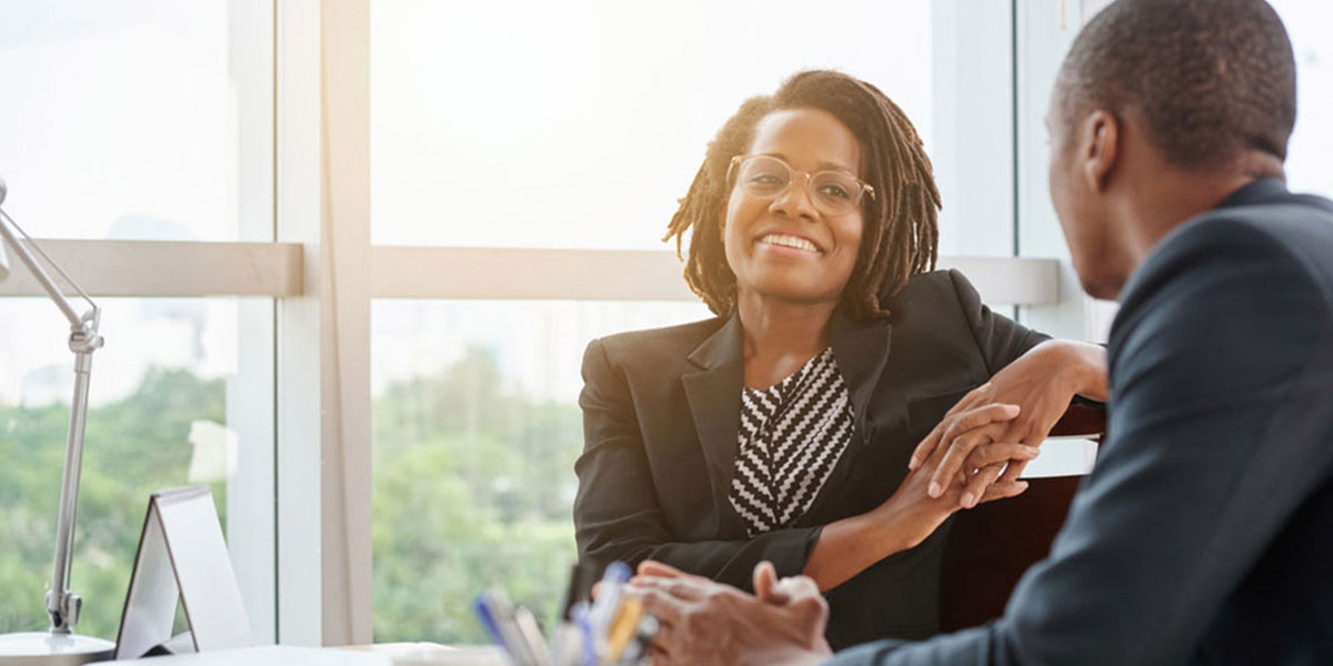 Executive coach sitting with a client in an office, discussing ways to enhance their leadership and business skills. 