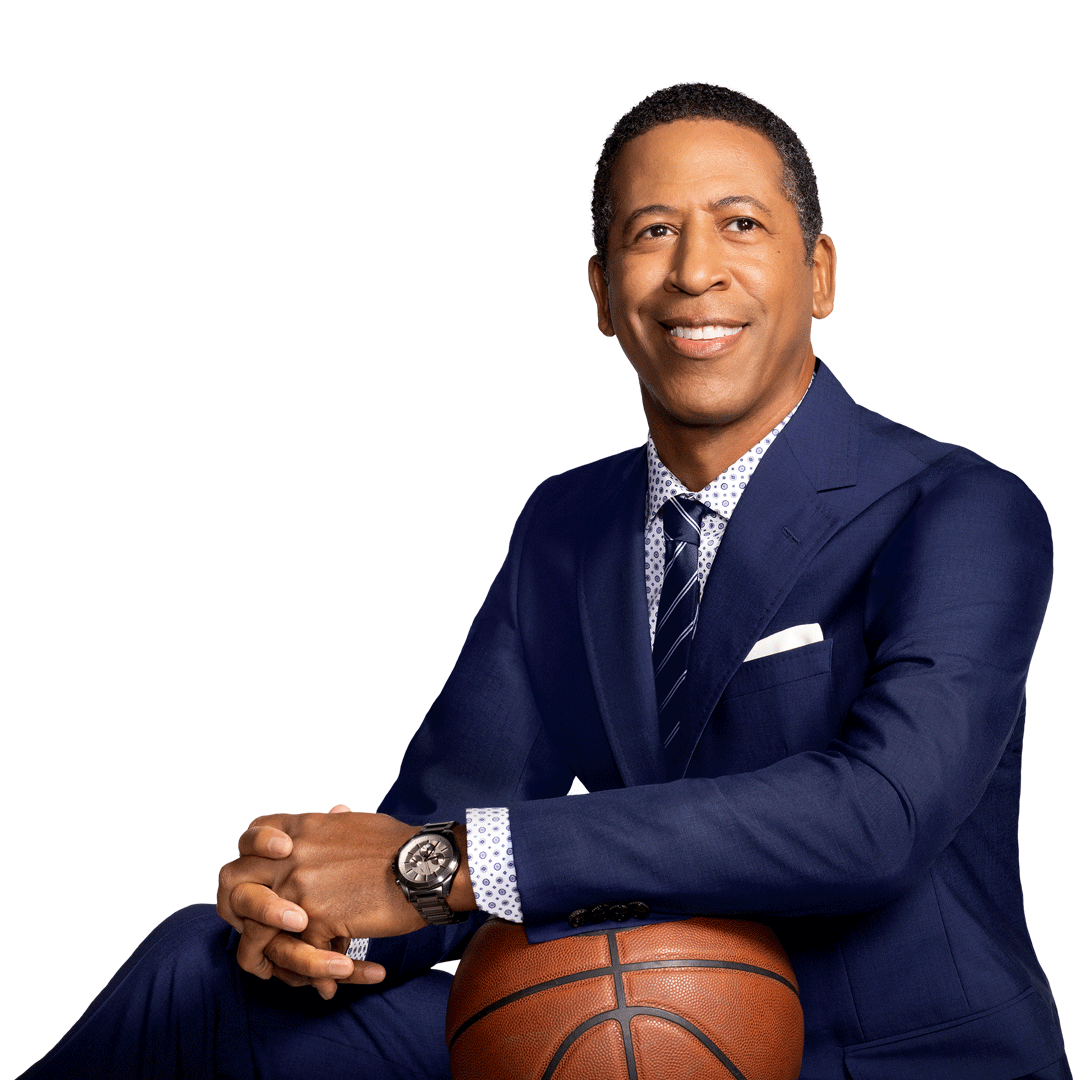 A man in a suit holing a basketball looking to his right