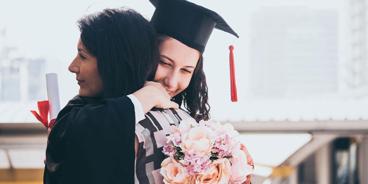 Mother and daughter hug at college graduation and daughter prepares to move home after graduating