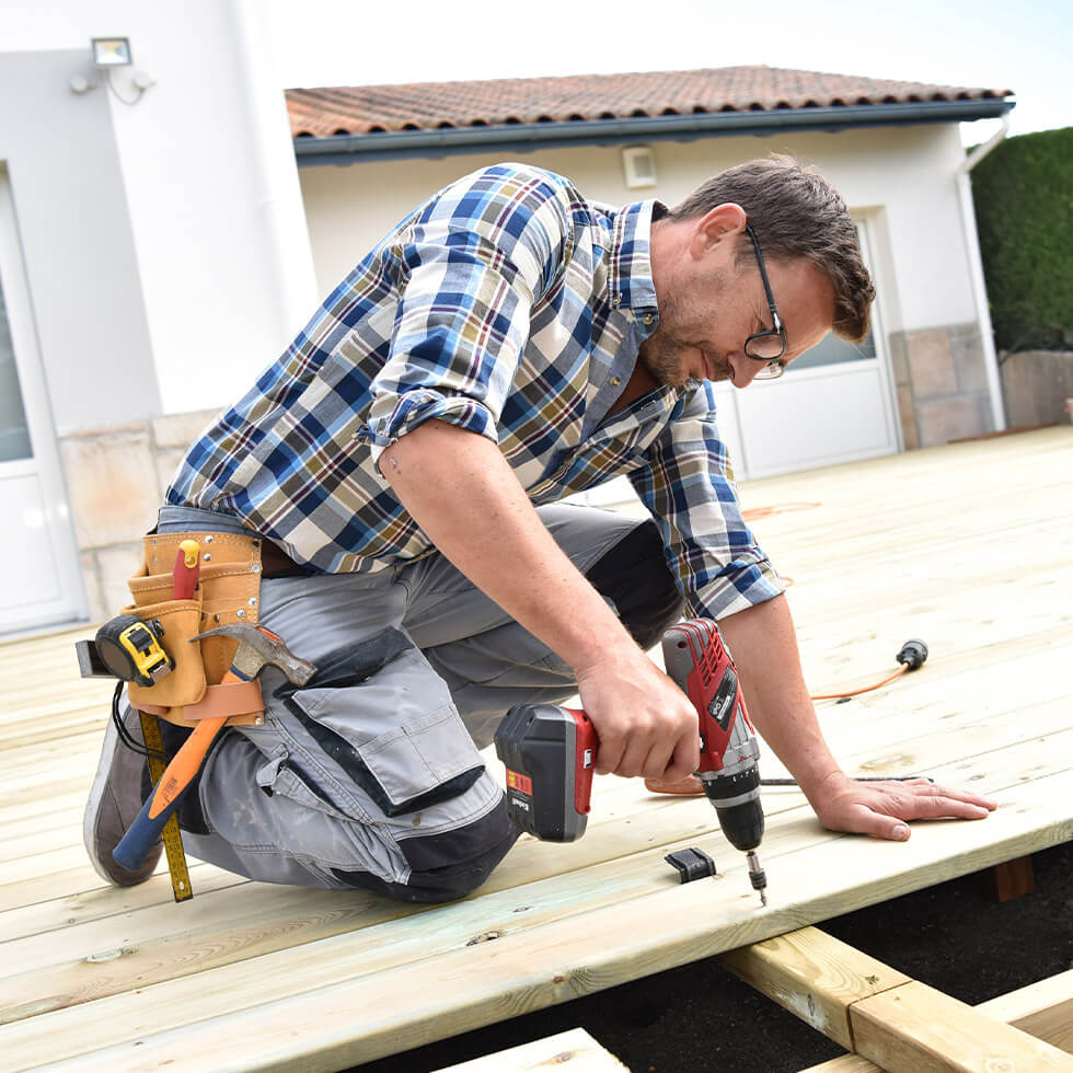 Man using drill to secure wood on deck after finalizing a home equity line of credit at City National Bank to complete the project