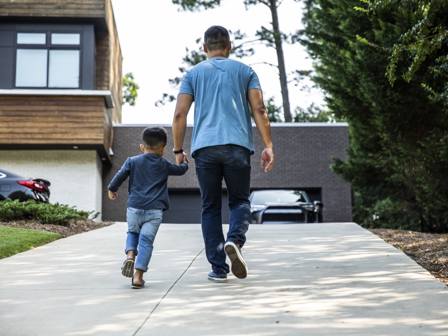 A father walking up the driveway with their son