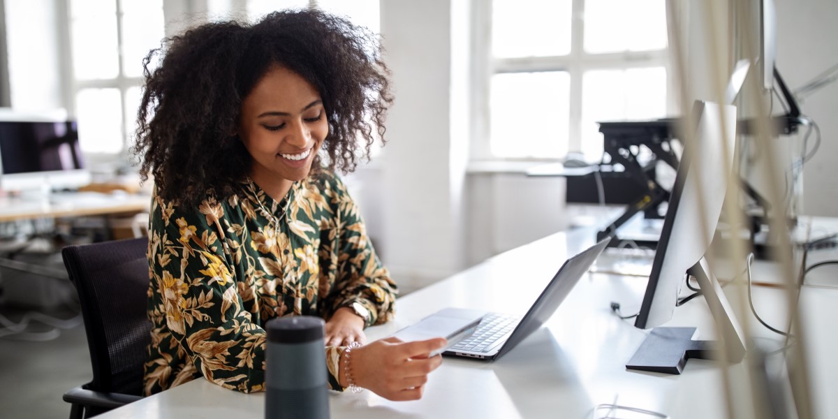 Woman looking at credit card and laptop