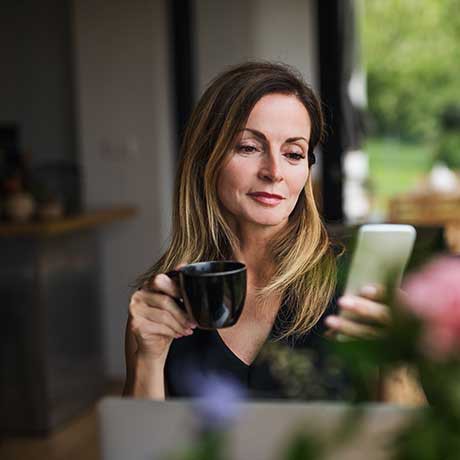 Woman drinking coffee deposits check on the City National Bank App