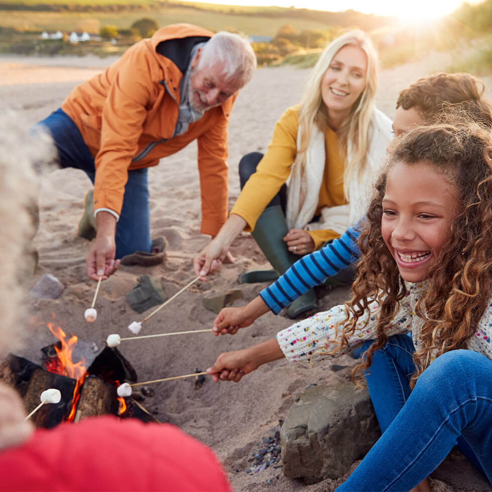 Family discussing City National Bank's trust estate services around the fire with marshmallows 